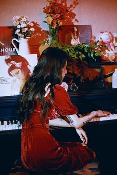 a woman in red dress sitting at a piano