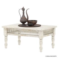 a white coffee table with two bowls and a tea pot on top