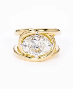 a yellow gold ring with an oval cut diamond in the center and two smaller bands around it