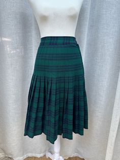 This is a beautiful skirt by Aljean Canada.  Plaid in green and navy colors.  Wool blend. Unlined, side zipper and button overlap closure. Marked size 14, fits size L us. Excellent vintage condition. Sizing is not marked but will fit US size S.  For a proper fit please see the measurements below. Measurements (flat): Waist: 25" Hips: 34" Shoulder to hem: 25,5" Fitted Green Pleated Skirt With Lining, Green Pleated Workwear Skirt With Lining, Green Pleated Skirt Lined For Workwear, Green Relaxed Fit Pleated Skirt For Work, Green Pleated Knee-length Bottoms, Retro Green Skirt For Fall, Green Knee-length Pleated Skirt For Workwear, Classic Green Pleated Skirt, Green Pleated Preppy Skirt