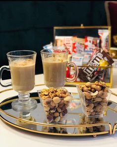 two cups filled with coffee and nuts on a tray