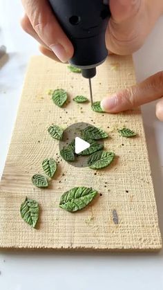 someone using a drill to cut leaves on a board