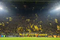 a soccer stadium filled with lots of fans and flags flying in the air at night