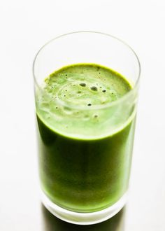 a glass filled with green liquid on top of a table