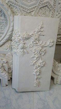 a white book sitting on top of a marble floor next to ornate carvings and mirrors