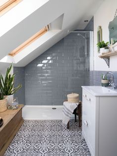 an attic bathroom with gray tile and white fixtures