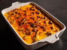 a casserole dish with meat and cheese in it on a black table top