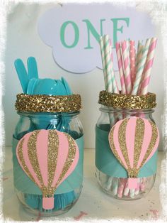 two mason jars with hot air balloons and paper straws in them are decorated with gold glitter