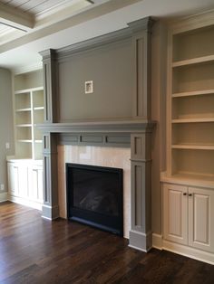 an empty living room with a fireplace and built - in bookcases