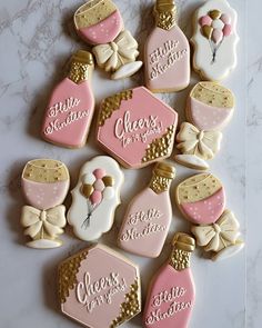 decorated cookies with pink and white frosting are arranged on a marble countertop in the shape of perfume bottles