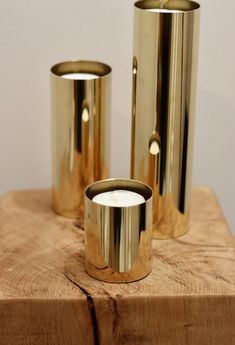 three brass vases sitting on top of a wooden block