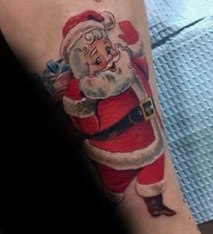 a person with a santa clause tattoo on their arm and leg, holding a christmas tree