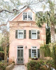 a pink house with green shutters and trees