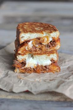 two grilled sandwiches stacked on top of each other with cheese and onions in between