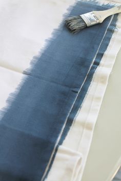 a paint brush sitting on top of a blue and white table cloth that has been dyed