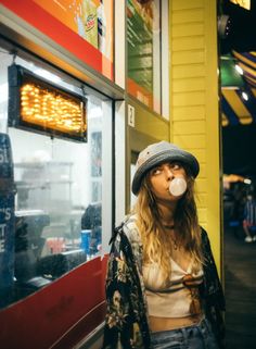 a woman blowing bubbles while standing in front of a food vending machine at night