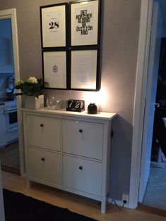 a white dresser with three framed pictures on top and two wine glasses sitting on it