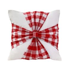 a red and white checkered pillow with a bow on the front, sitting on a white surface