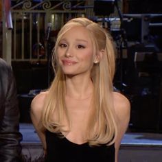 a woman with long blonde hair sitting next to a man in a black suit and tie