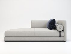 a white couch with pillows on it in front of a white wall and grey floor