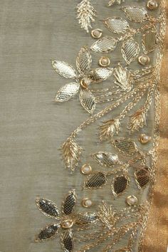 a piece of cloth with gold thread and beads on it