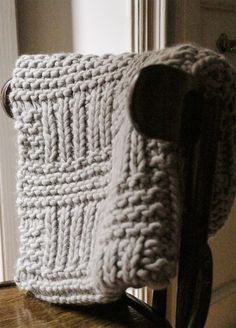 a crocheted pillow sitting on top of a wooden chair next to a door