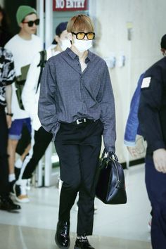 a man wearing a mask and carrying a handbag while walking down the runway at an airport