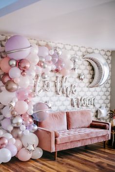 a living room filled with balloons and stars on the wall next to a pink couch