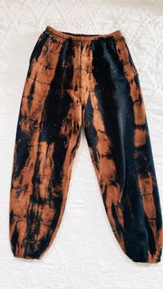 an orange and black tie - dyed pants laying on top of a bed