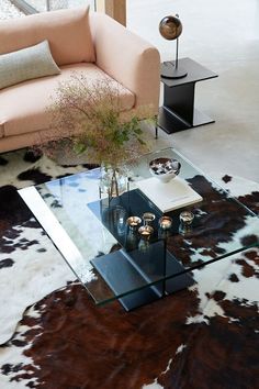 a living room with a couch, table and cow hide rug on the floor in front of it