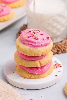 a stack of cookies with pink frosting and sprinkles on a plate