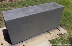 a large metal box sitting on top of a wooden pallet in the middle of some grass