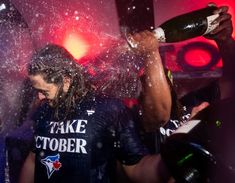 a man is pouring champagne into his face as he stands in front of a crowd