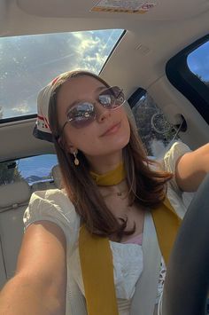 a woman sitting in the back seat of a car wearing sunglasses and a bandana