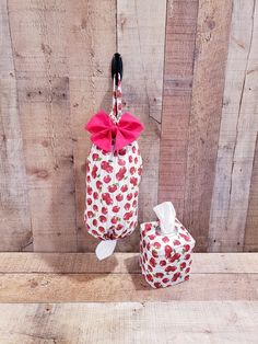 two red apples wrapped in white paper and tied to a hook on a wooden wall