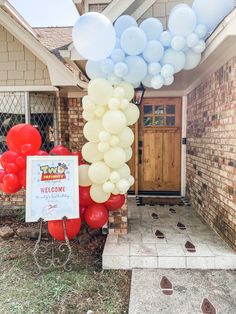 balloons are attached to a welcome sign in front of a house