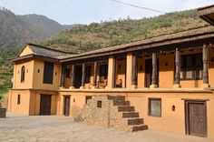 an old building with stone steps leading up to it and mountains in the back ground