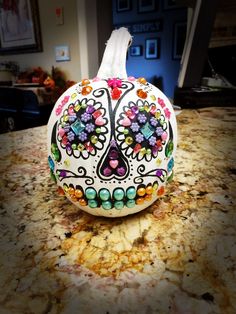 a white pumpkin decorated with multicolored sugar skulls