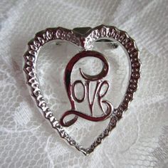 a heart shaped brooch with the letter b in it's center on a white lace background