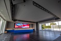 an empty room with large windows and a flat screen tv on the wall in front of it