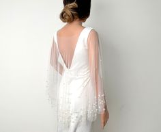 the back of a woman's white dress with sheer sleeves and beaded details