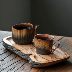 two cups are sitting on a wooden tray