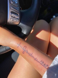 a woman with a tattoo on her arm sitting in a car