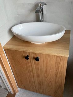 a white bowl sink sitting on top of a wooden cabinet