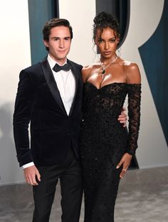 a man in a tuxedo standing next to a woman in a black dress