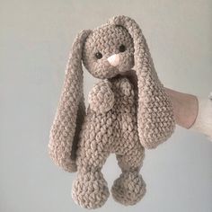 a crocheted stuffed animal is being held in the air by someone's hand