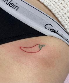 a woman's stomach with a red chili tattoo on her left side ribcage