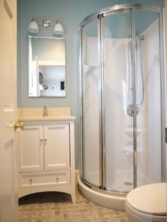 a bathroom with a walk in shower next to a white sink and toilet under a mirror