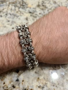 a man's arm with a silver chain bracelet on it