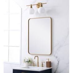 a bathroom vanity with a mirror and two lights on the wall, along with a gold faucet